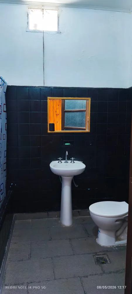 Baño con lavatorio, inodoro y sector de ducha con cortina.
