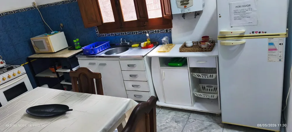 Cocina con heladera, cocina a gas, mesada y mesa de comedor.